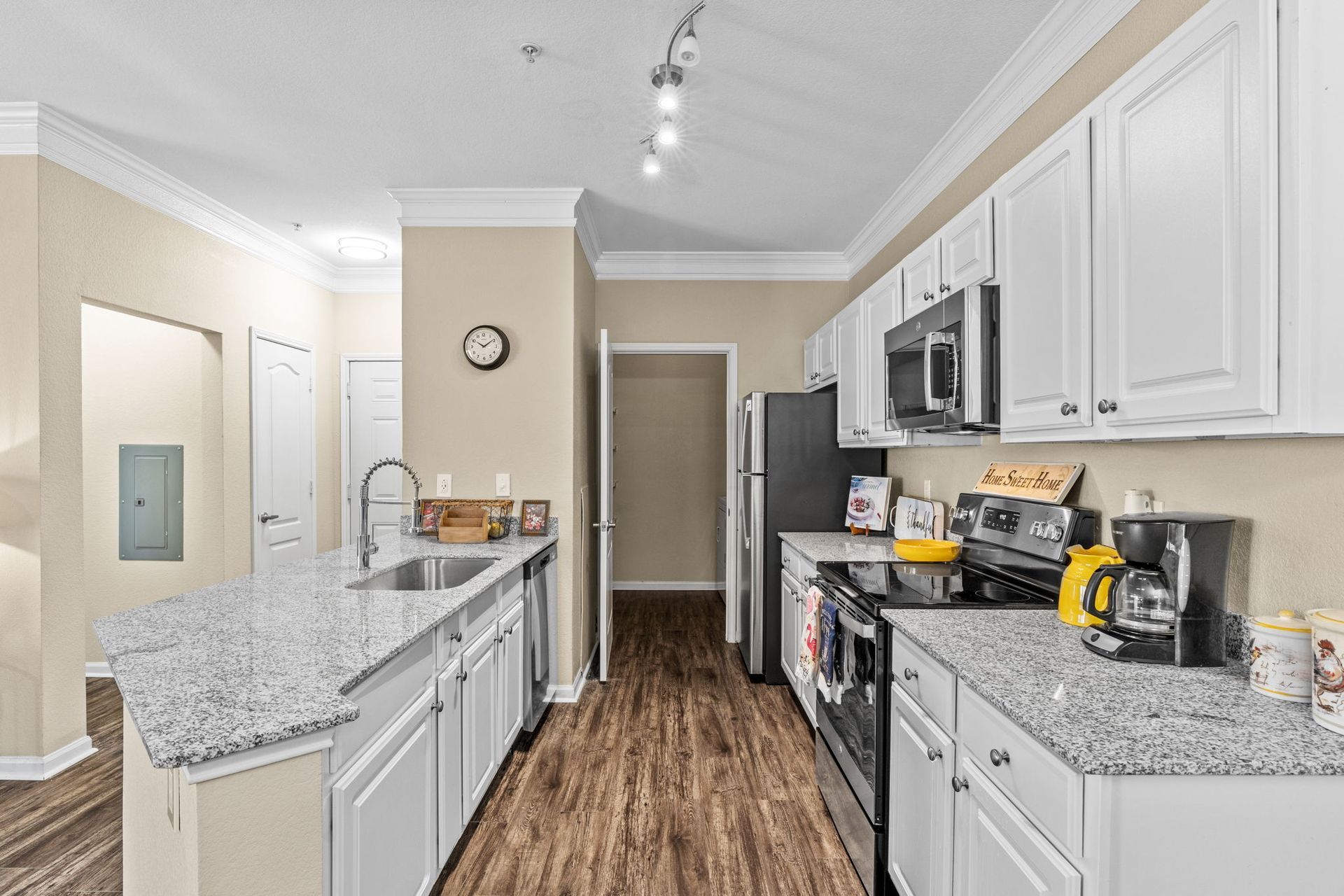 A kitchen with white cabinets , granite counter tops , stainless steel appliances and a clock on the wall at Reserve at Long Point.