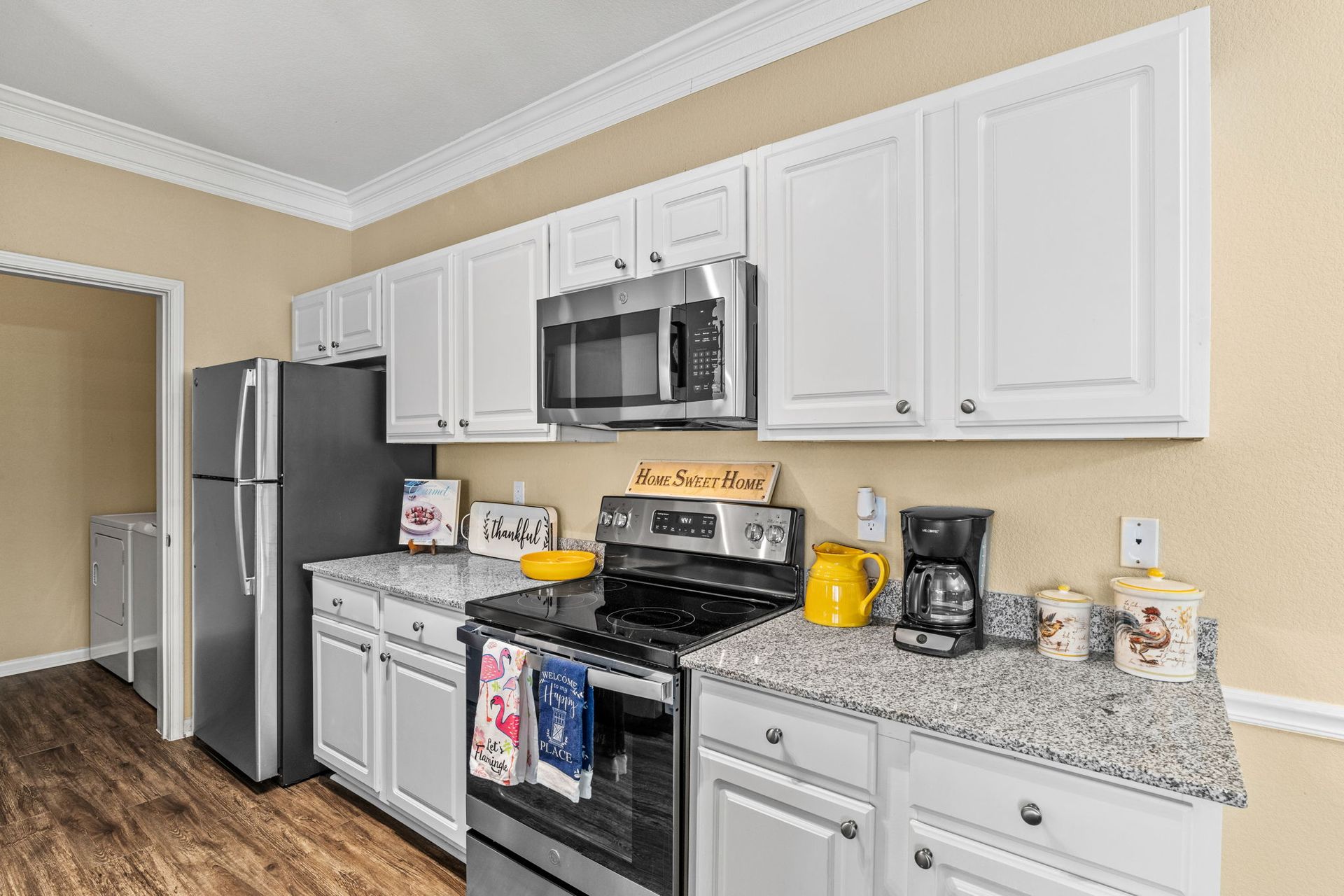 A kitchen with white cabinets , stainless steel appliances , a refrigerator , stove , microwave and sink at Reserve at Long Point.