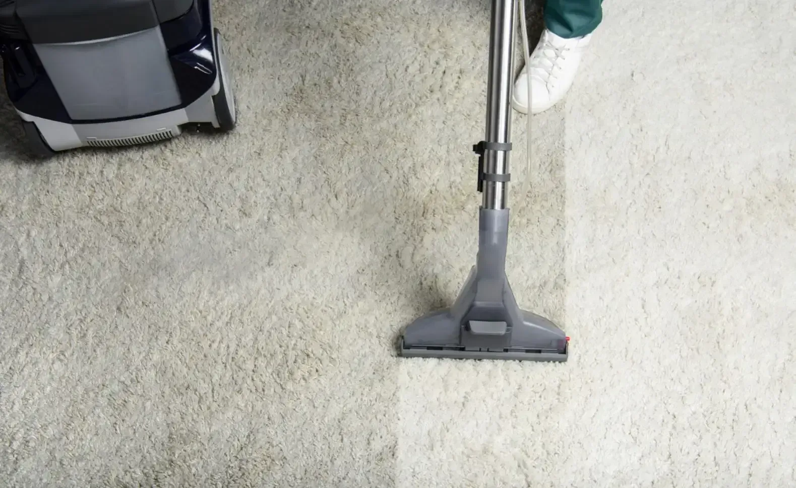 A person is using a vacuum cleaner to clean a carpet. — Lake Macquarie Carpet Cleaning In Warners Bay, NSW