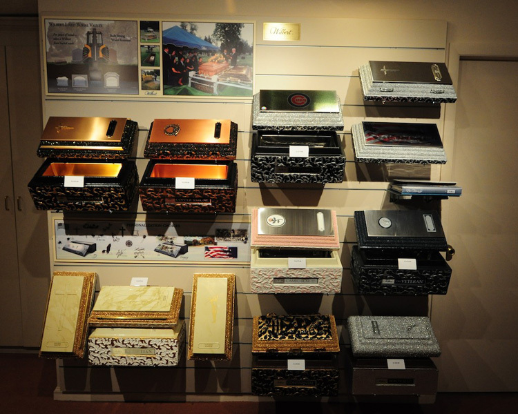 Display of decorative boxes in various colors and designs, mounted on a wall.