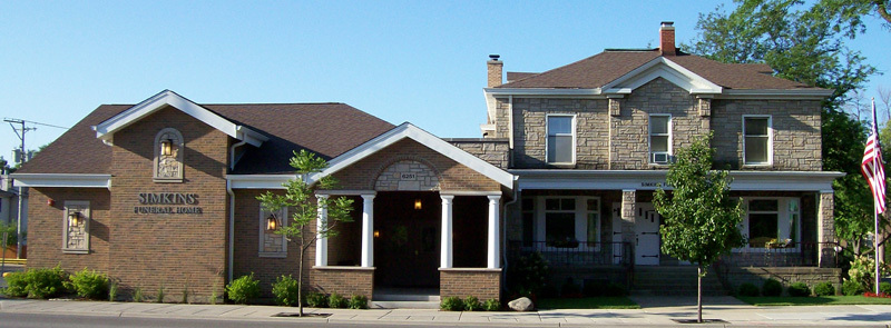A two-story building with a brick facade on the left and stone on the right, under a clear blue sky.