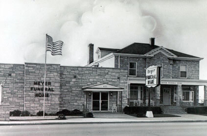 Meyer Funeral Home, a stone building with an American flag; vintage.