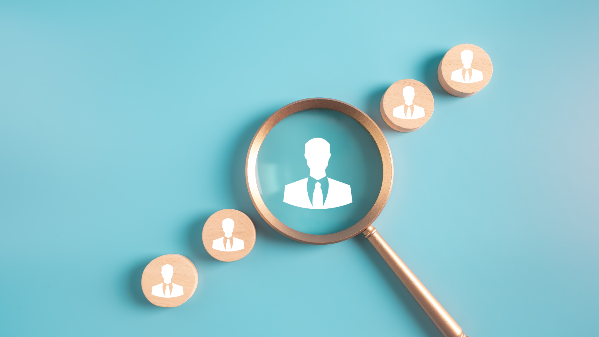 Magnifying glass over a person icon, surrounded by more person icons on a blue background, representing recruitment.