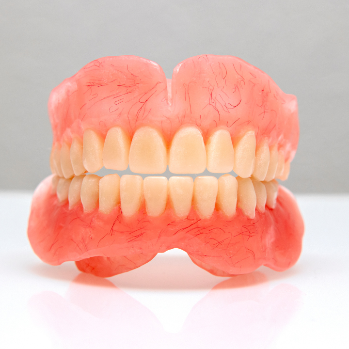 A full denture is sitting on a white surface.