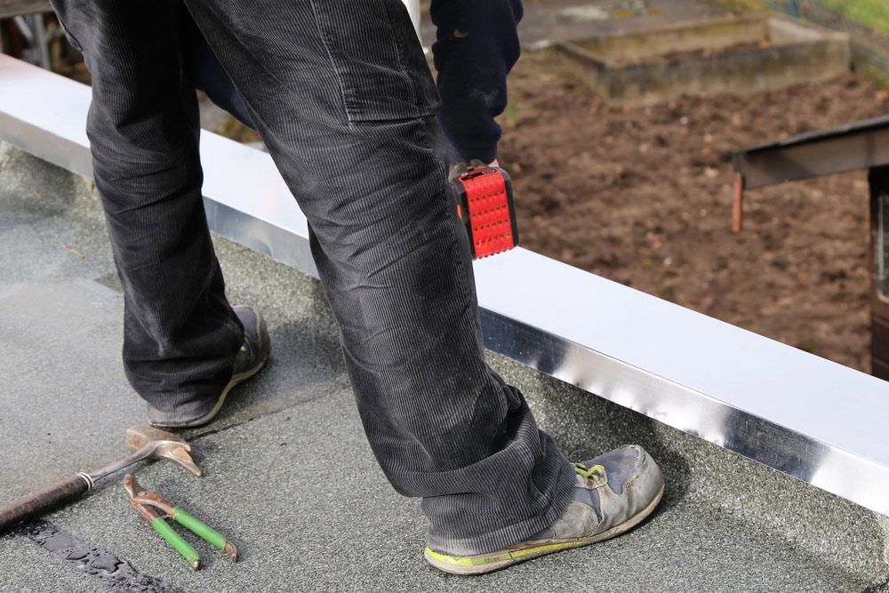 A Man Is Standing on A Roof with A Saw and Hammer — FBM Fabrication In Wollongong, NSW