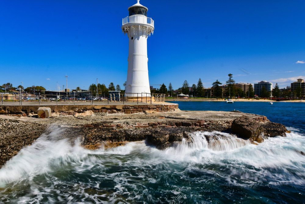 A Lighthouse Is Sitting on Top of A Rocky Cliff Overlooking the Ocean — FBM Fabrication In Wollongong, NSW