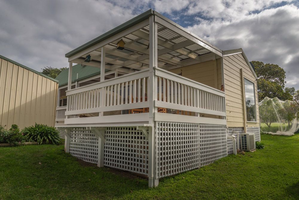A Small House with A Porch and A Fence in Front of It — FBM Fabrication In Nowra, NSW