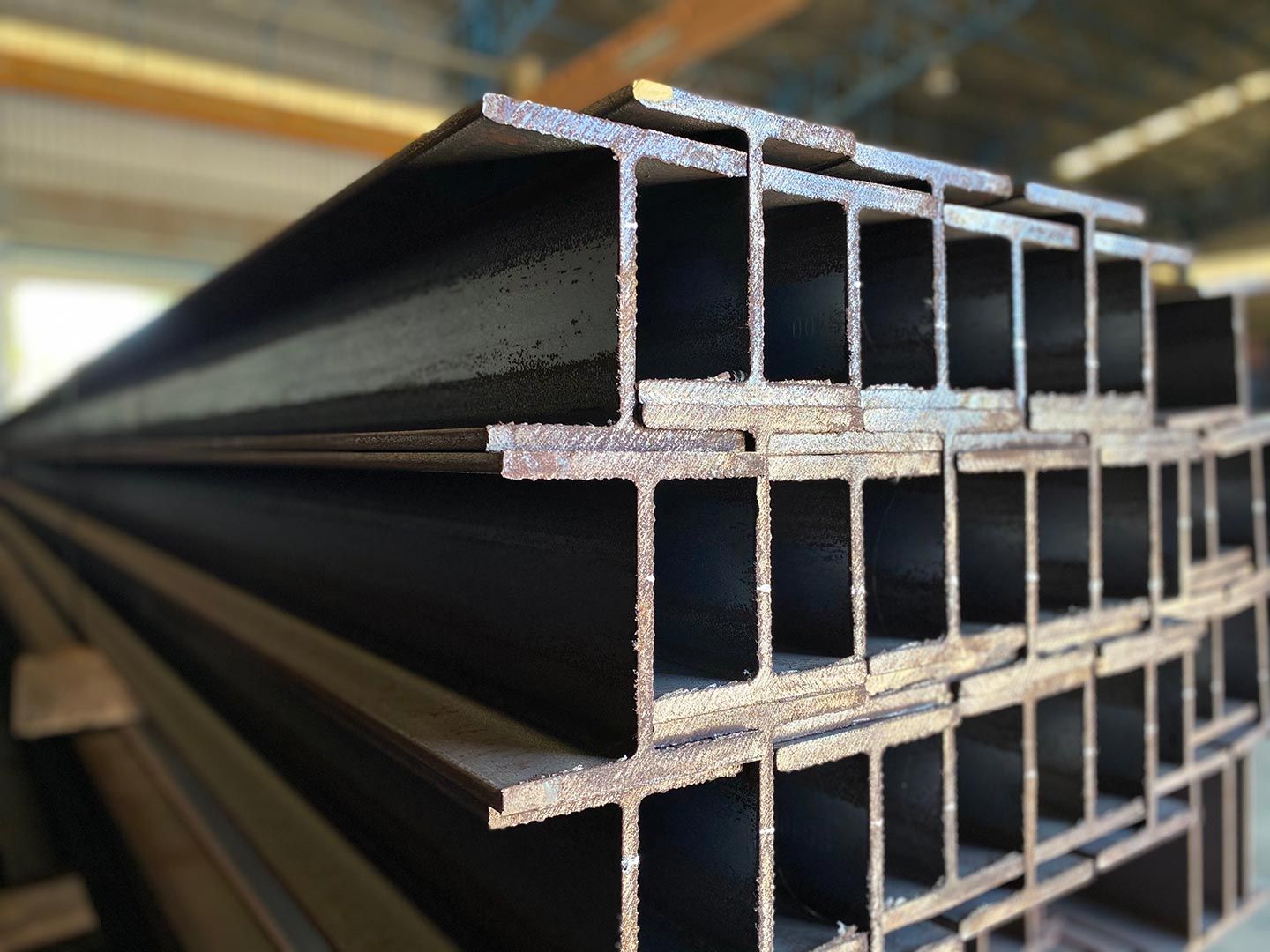 A Stack of Steel Beams Are Stacked on Top of Each Other in A Warehouse — FBM Fabrication In Dapto, NSW