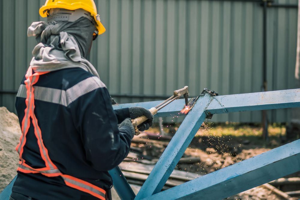 A Man Is Welding A Metal Structure With A Torch — FBM Fabrication In Dapto, NSW
