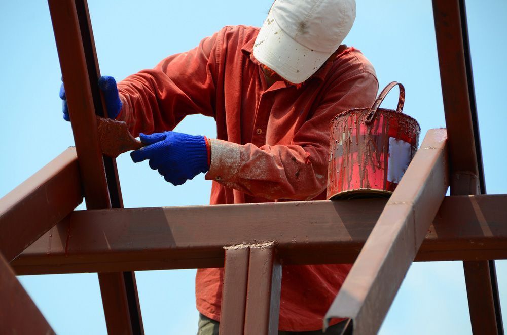 A Man Is Painting a Metal Structure with A Brush — FBM Fabrication In Shellharbour, NSW