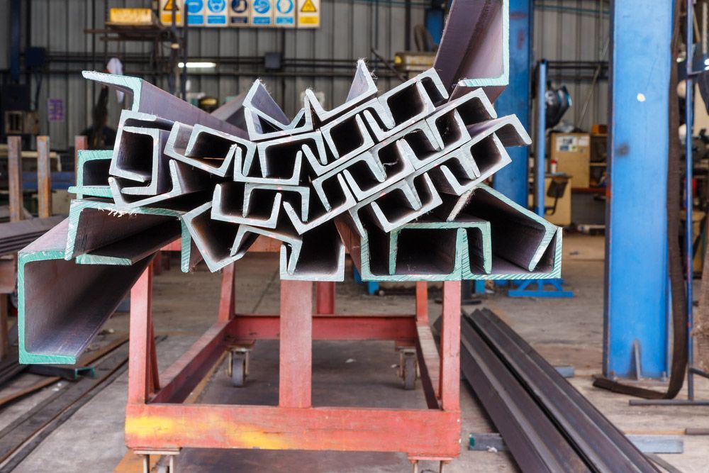 A Bunch of Metal Pieces Are Stacked on Top of Each Other on A Cart in A Factory — FBM Fabrication In Nowra, NSW