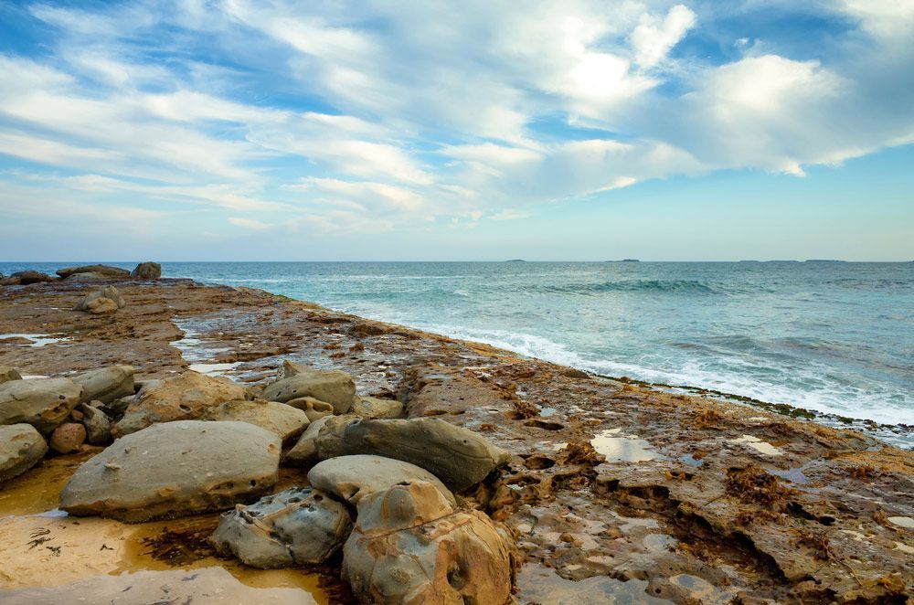 There Are a Lot of Rocks on The Beach Near the Ocean — FBM Fabrication In Wollongong , NSW