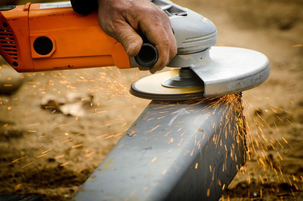 A Person Is Grinding a Piece of Metal with A Grinder — FBM Fabrication In Shellharbour, NSW