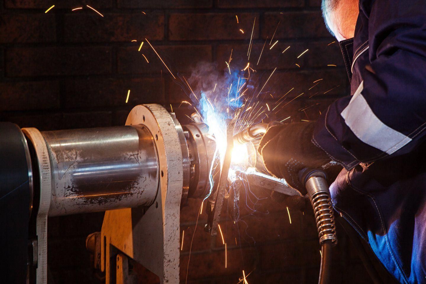 A Man Is Welding a Metal Pipe in A Factory — FBM Fabrication In Shellharbour, NSW