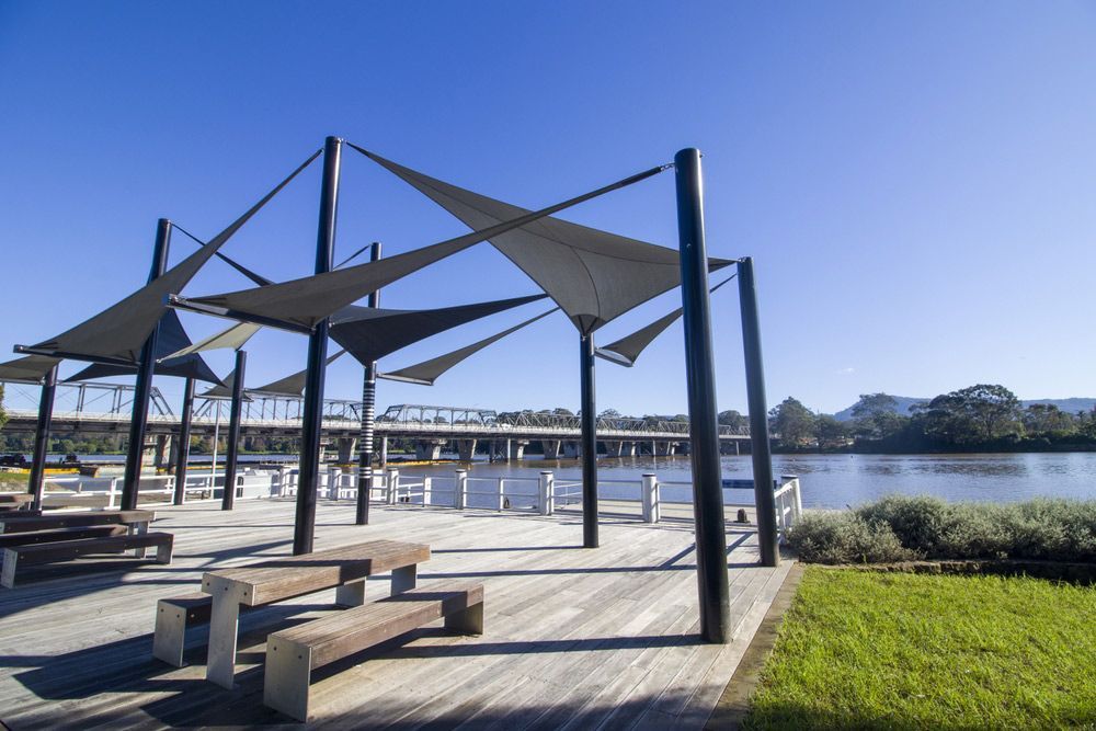 A Wooden Deck with Benches and Umbrellas Overlooking a Body of Water — FBM Fabrication In Nowra, NSW