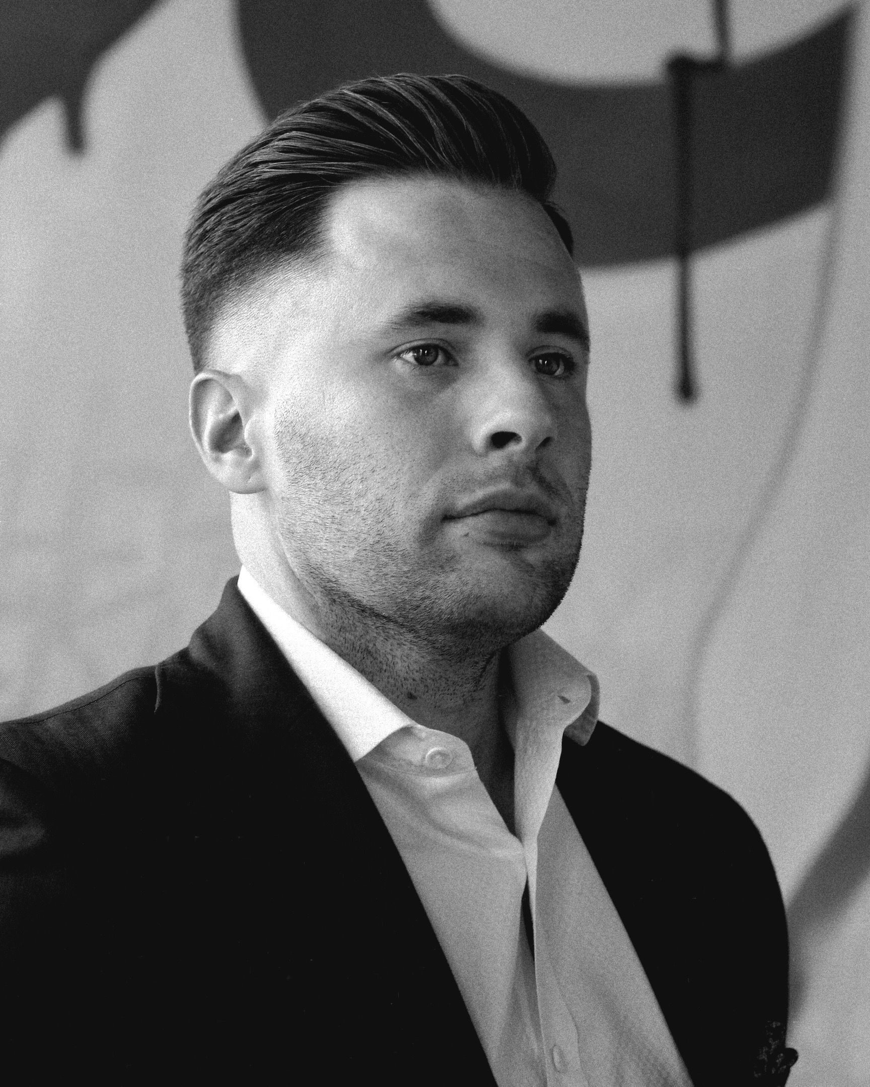 Man in suit, short hair, looking thoughtful. Black and white photo.