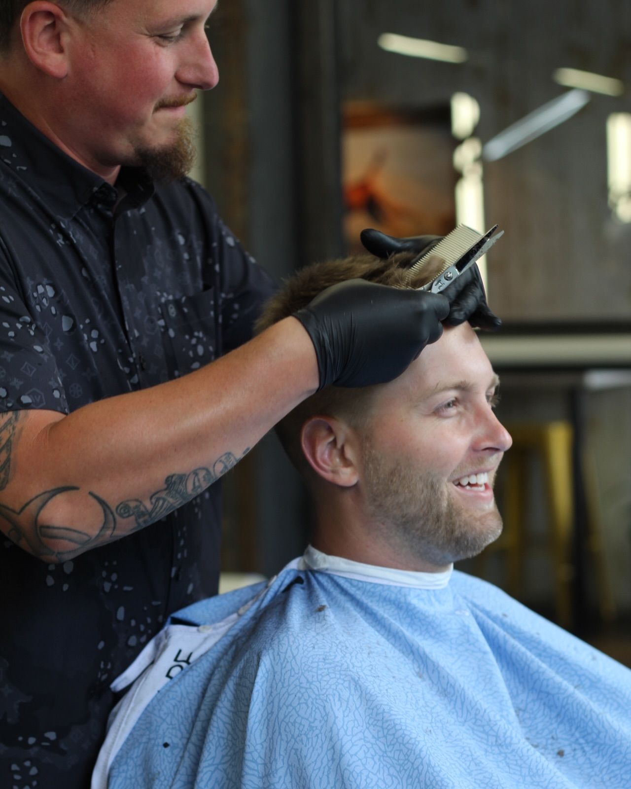 Barber giving a haircut to a smiling man in a barbershop.