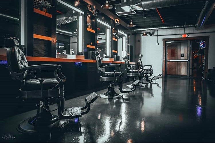 A barbershop interior with black chairs, mirrors, and a glossy floor.