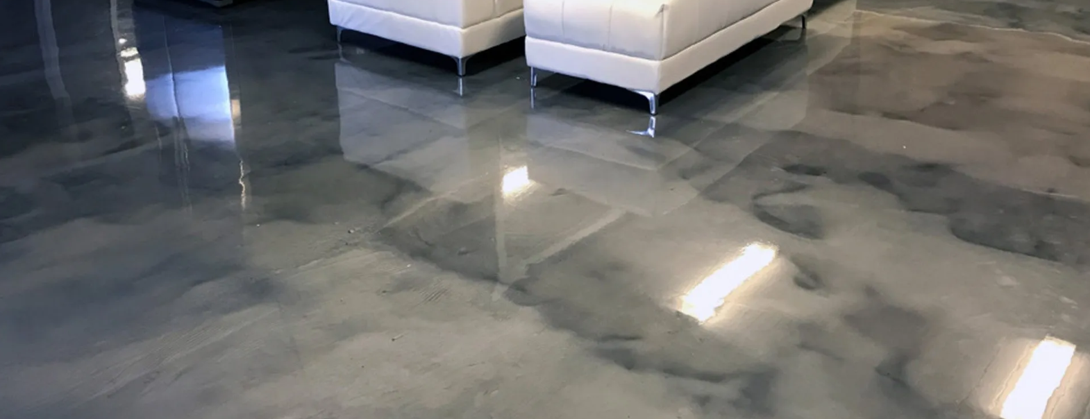 Shiny, metallic-looking floor with reflections. Two white couches are in the background, out of focus.