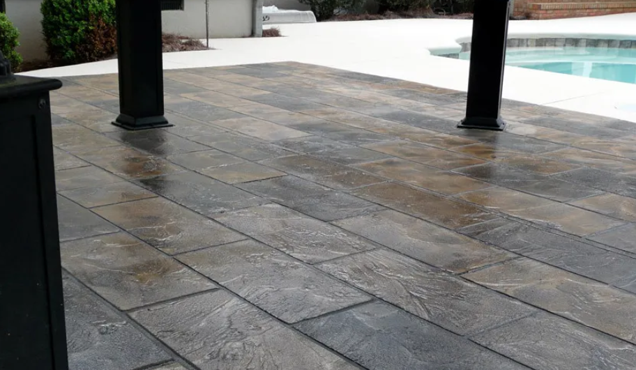 Stamped concrete patio with a wood-grain pattern and pillars near a swimming pool.