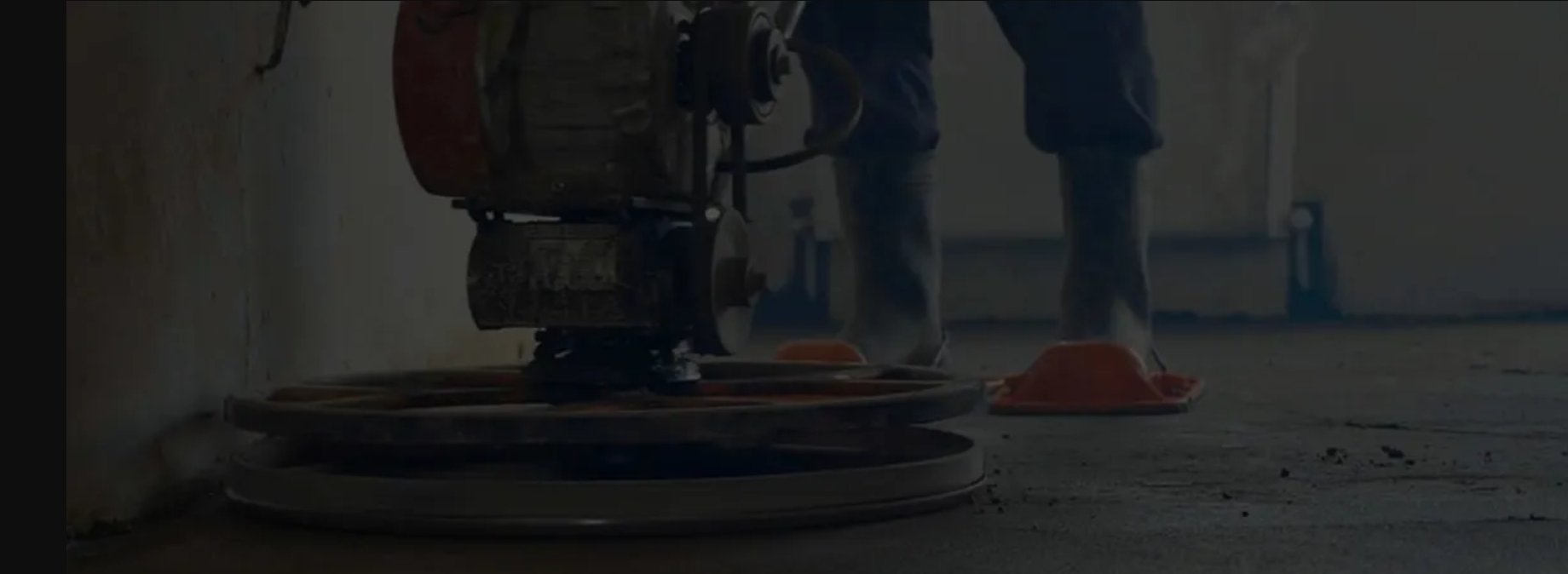 Person using a floor grinder. They are standing in an indoor setting with orange cones.