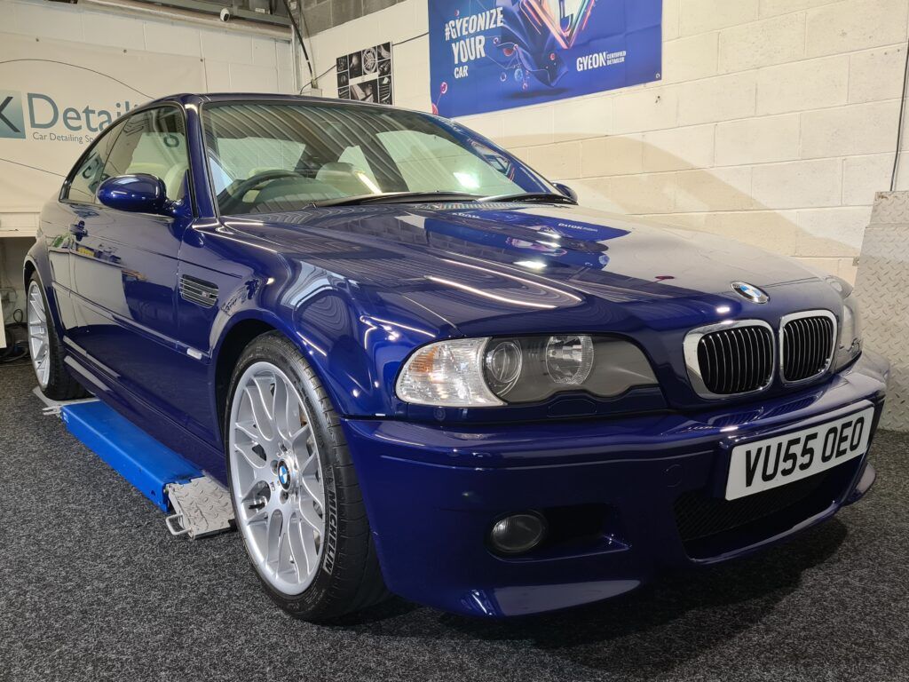 A blue bmw is parked on a lift in a garage.