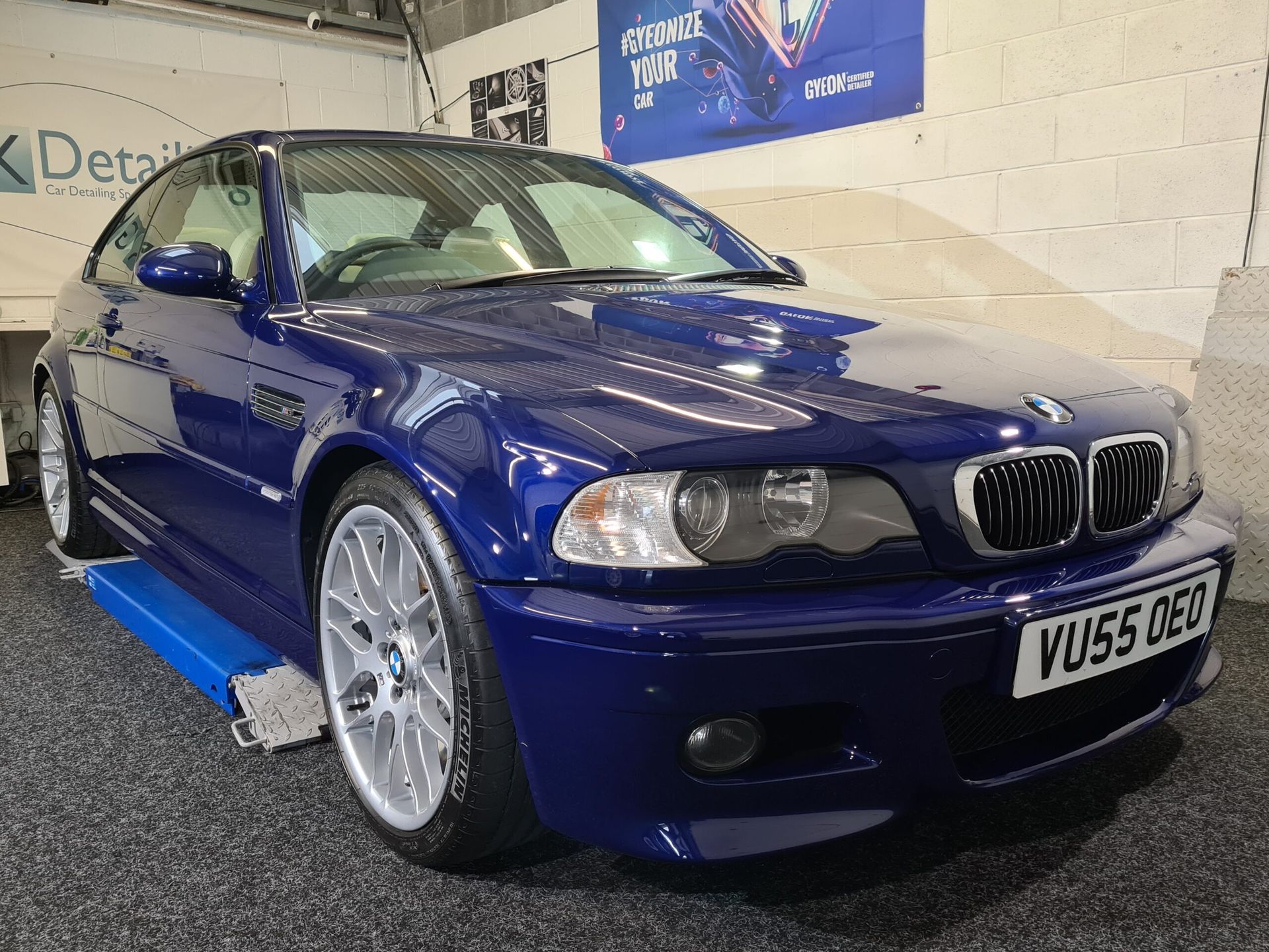 A blue bmw is parked on a lift in a garage.