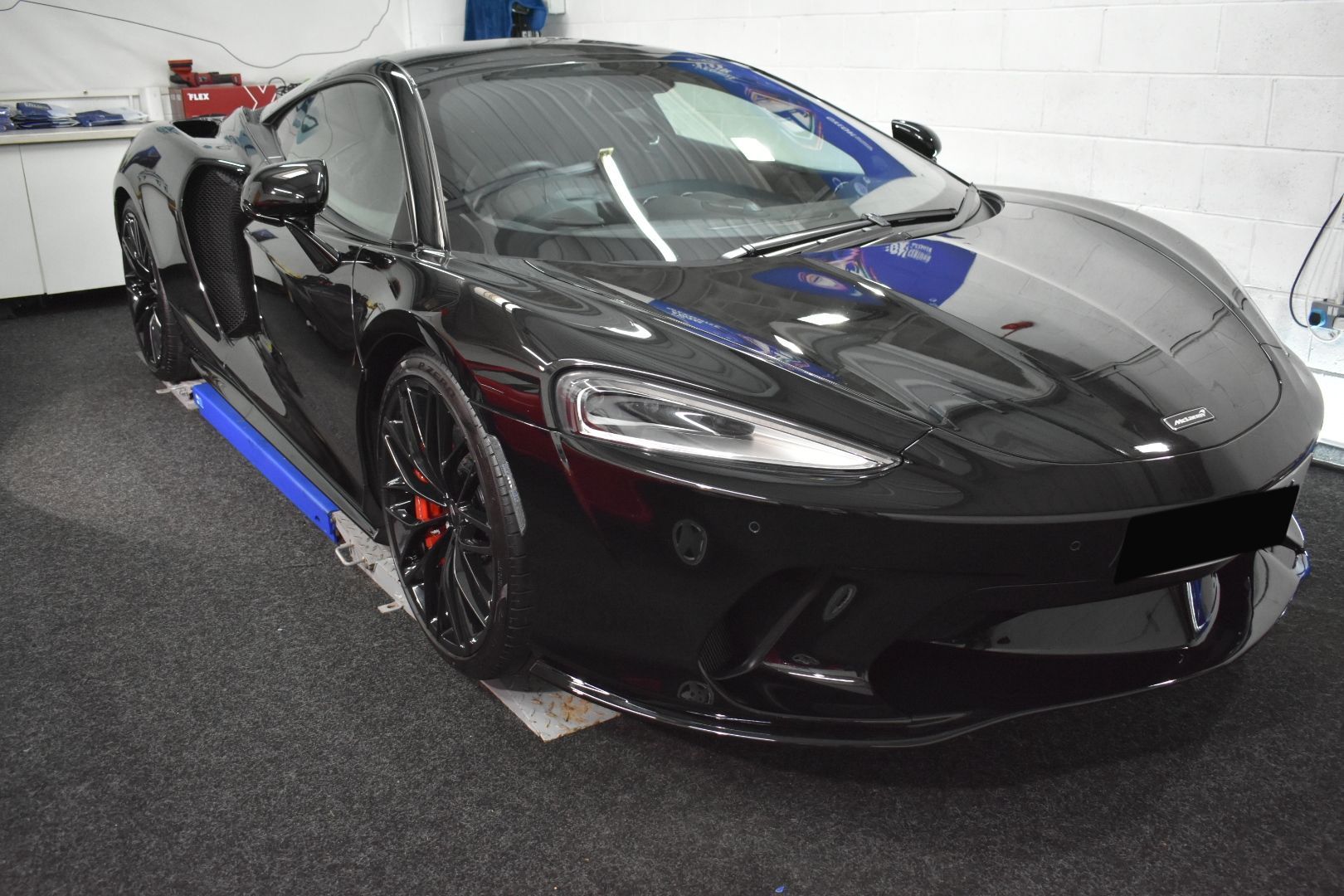 A black sports car is parked in a garage.