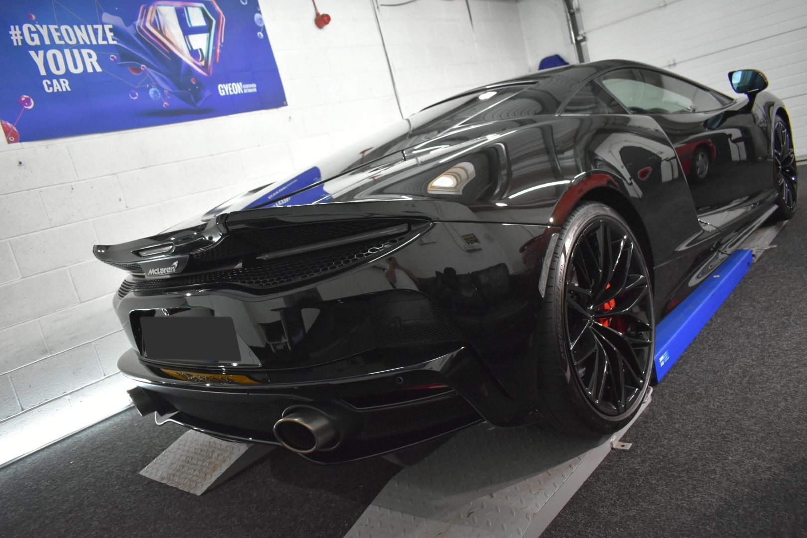 A black sports car is sitting on a lift in a garage.