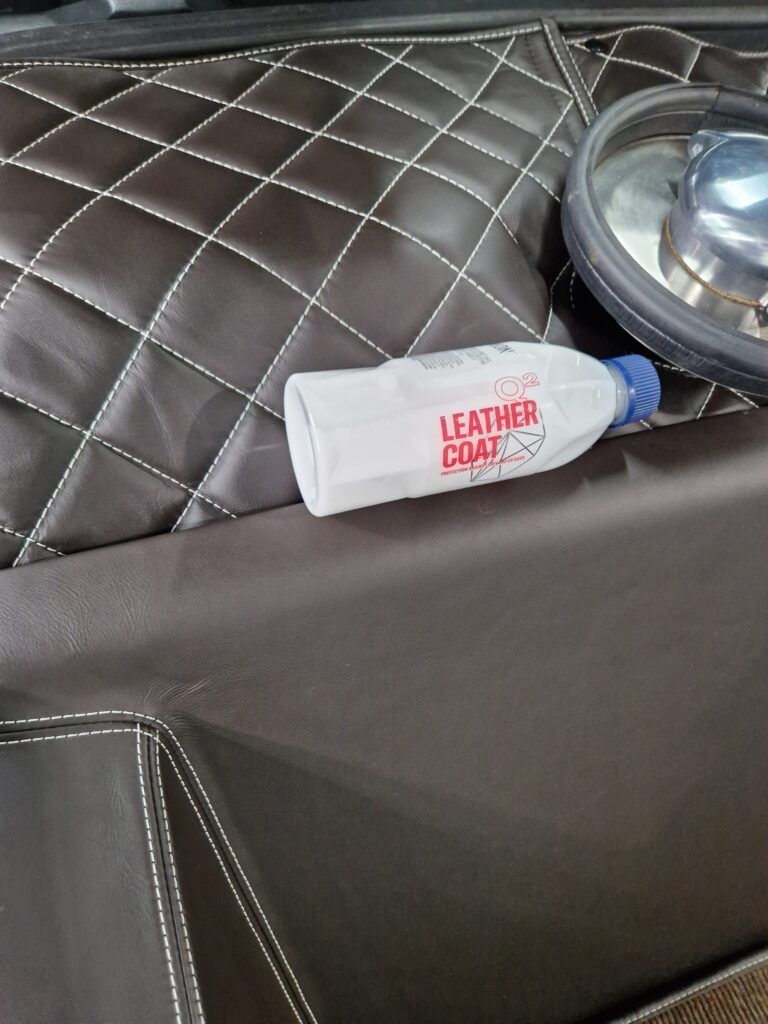 A bottle of leather coat is sitting on top of a couch.