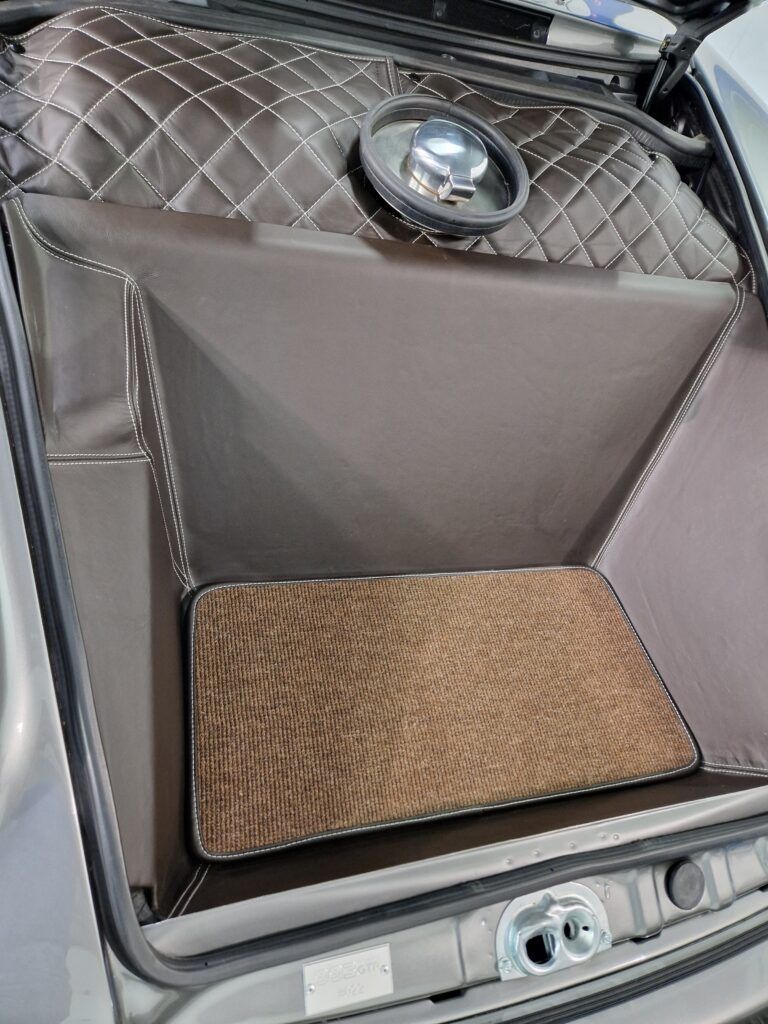 The trunk of a car with a speaker and a mat in it.