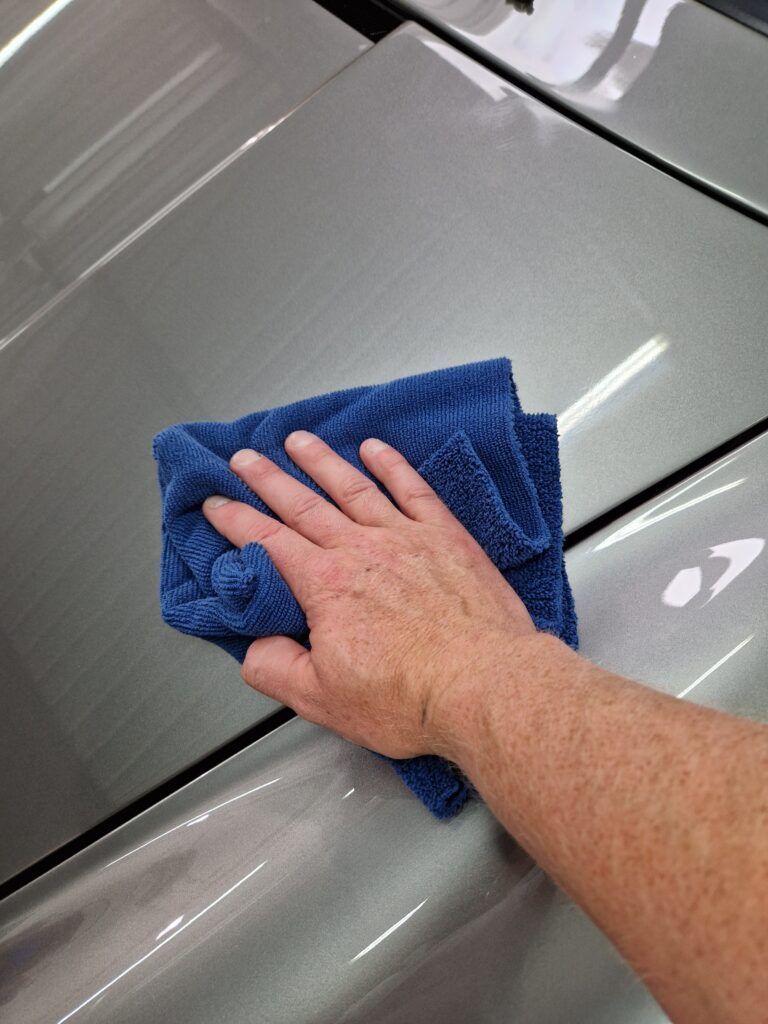 A person is cleaning a car with a blue towel.
