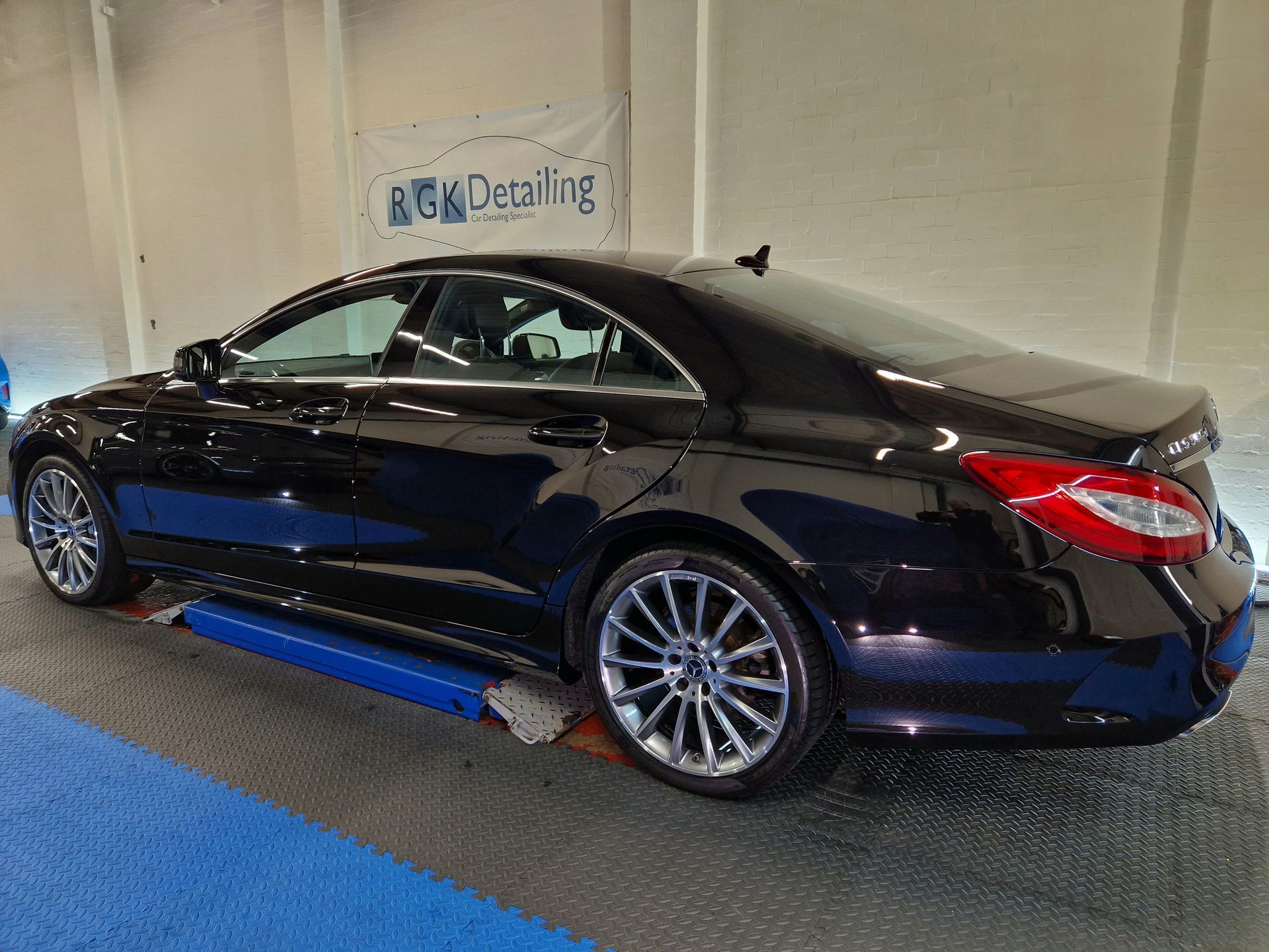 A silver volkswagen golf is sitting on a lift in a garage.