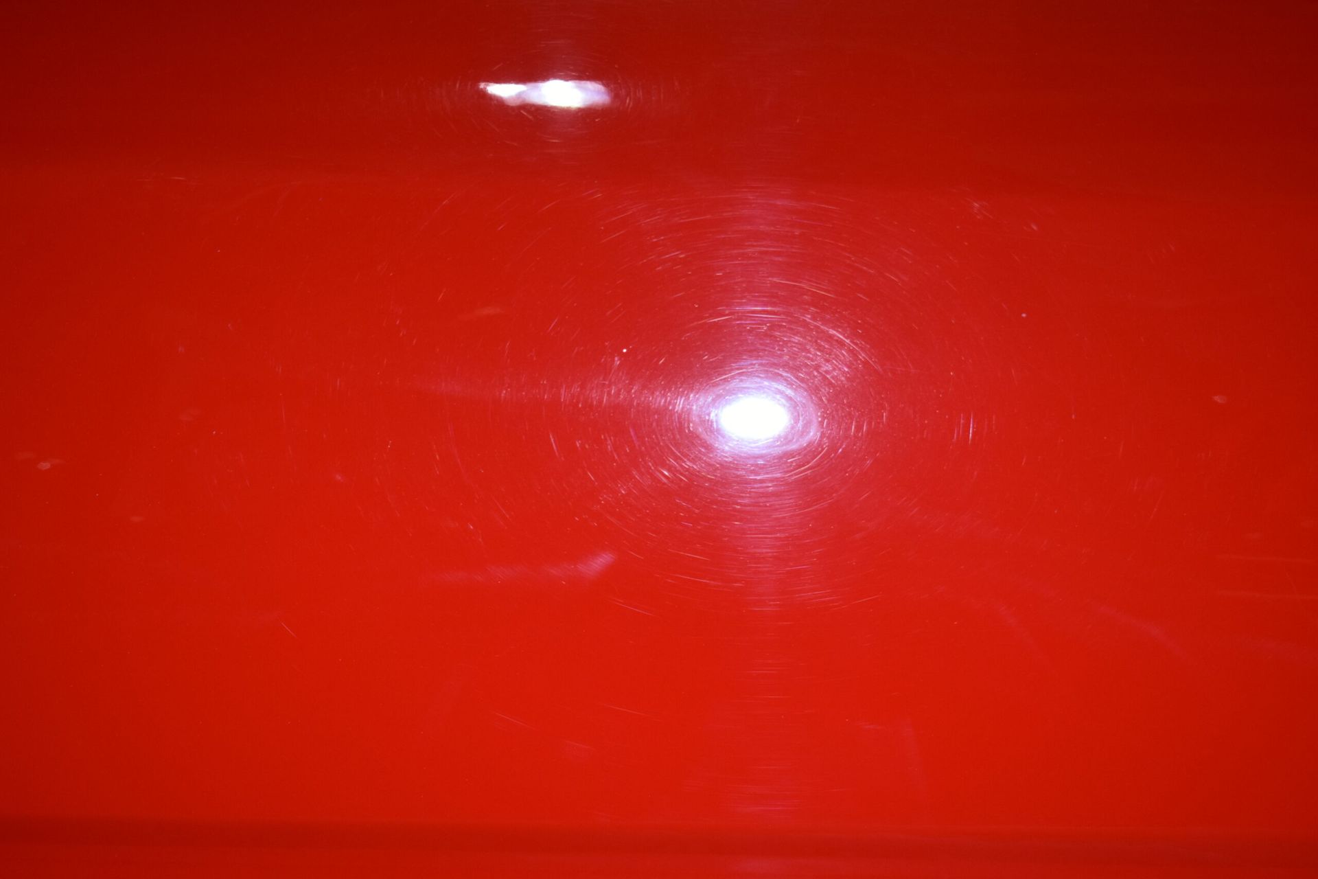 A close up of a red surface with a light shining on it.