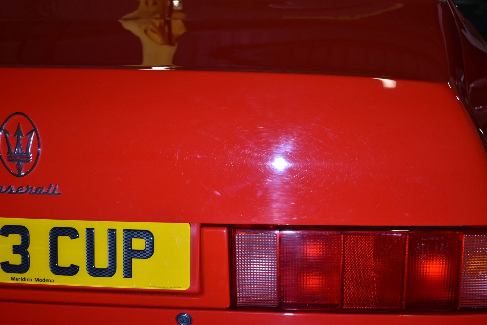 A red car with a license plate that says 3 cup