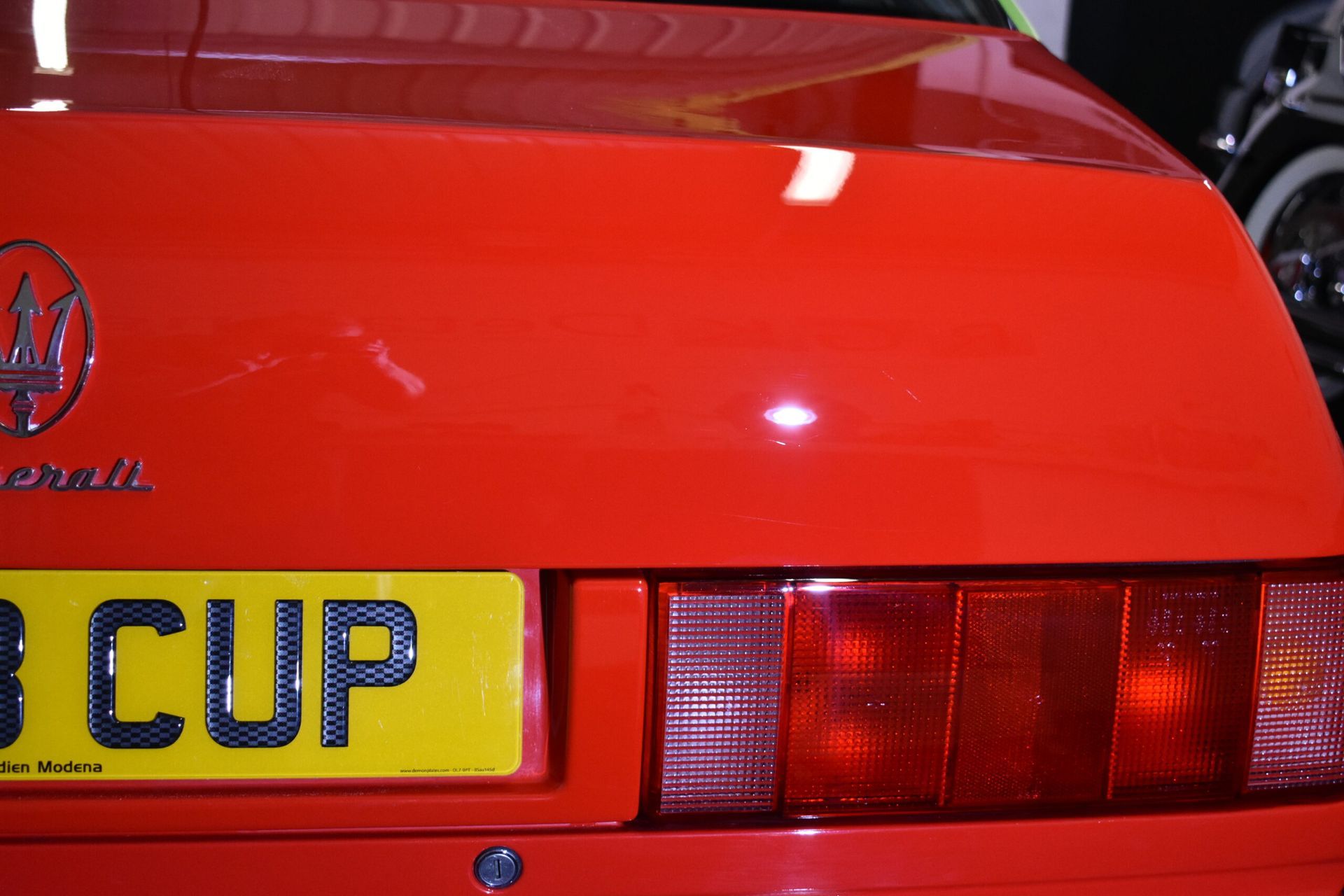 A red car with a license plate that says 3 cup
