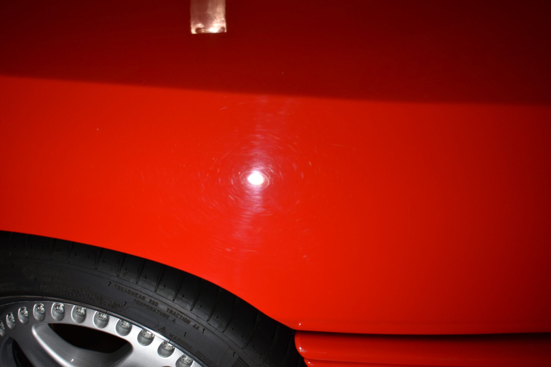 A close up of a red car with a tire on it.