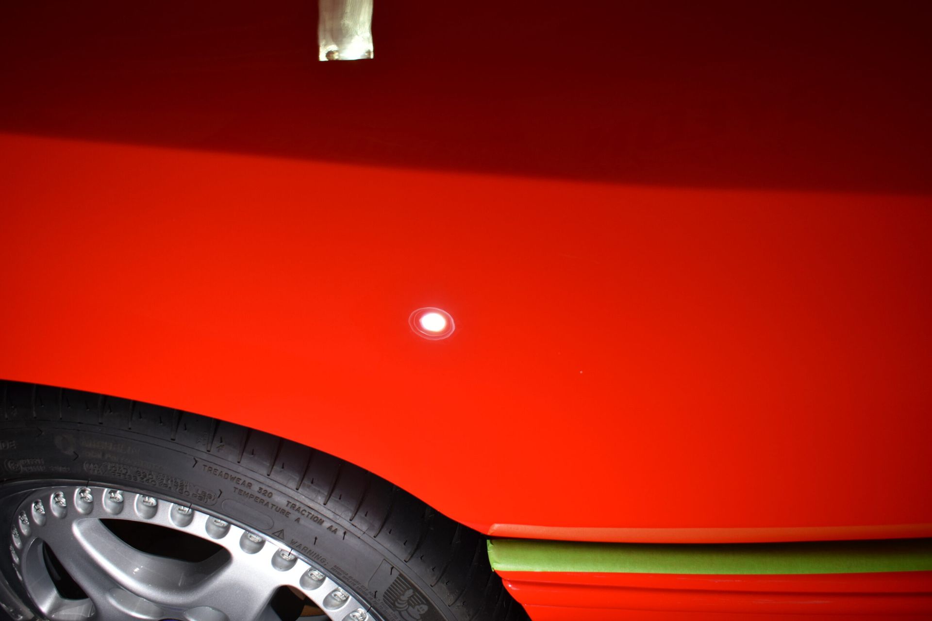 A close up of a red car with a tire on it.