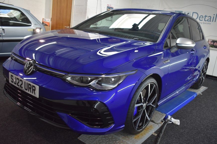 A blue volkswagen golf r is sitting on a lift in a garage.
