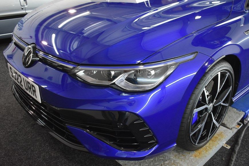 A blue volkswagen golf r is sitting on a table in a showroom.