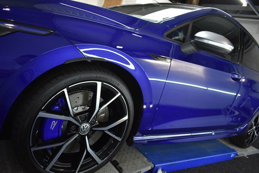 A blue car is parked on a lift in a garage.
