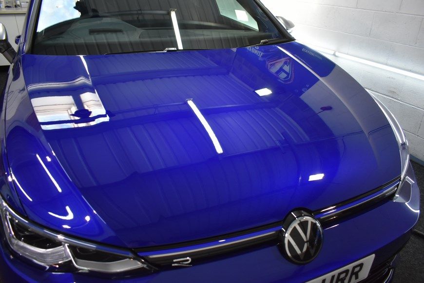 A blue volkswagen golf is parked in a garage