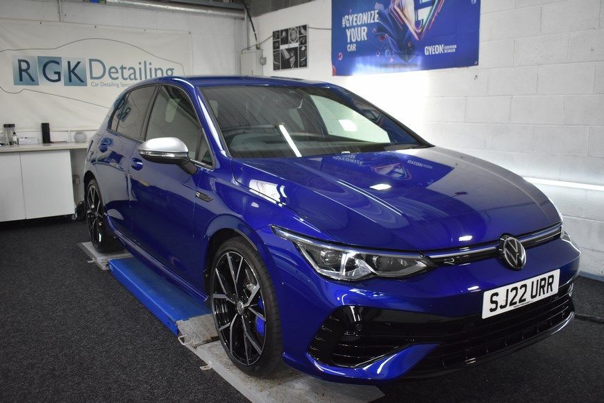 A blue volkswagen golf r is sitting on a lift in a garage.