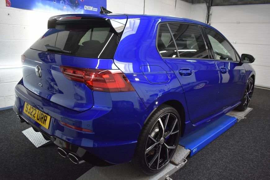 A blue volkswagen golf r is being tested in a garage.