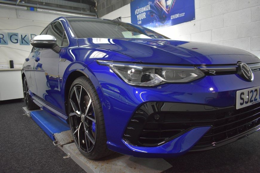 A blue car is parked on a lift in a garage.
