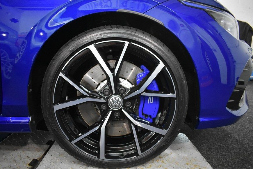 A close up of a blue car wheel with blue brake calipers.