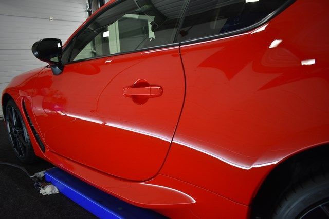 A red car is sitting on a lift in a garage.