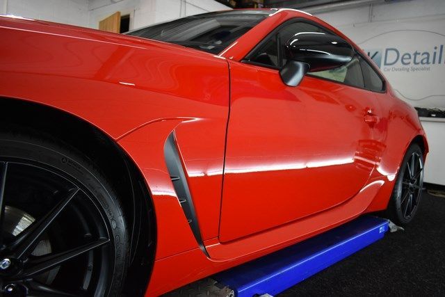 A red sports car is on a lift in a garage