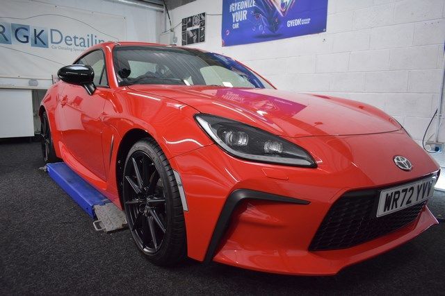 A red sports car is parked on a lift in a garage.