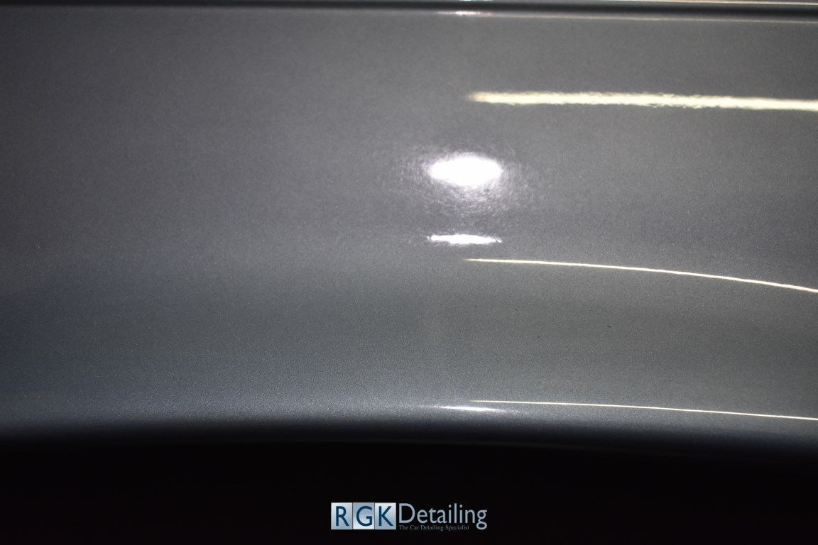 A close up of a gray car with a light shining on it.